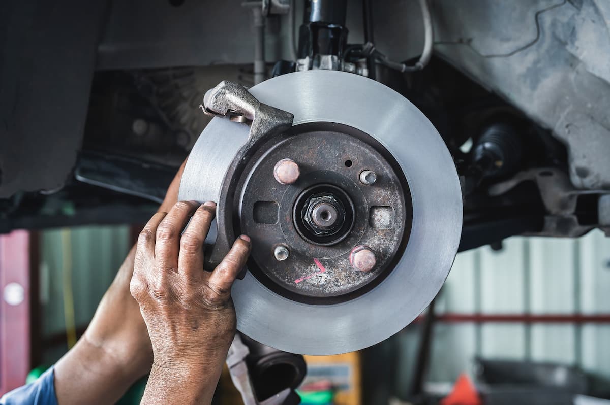Professional brake rotor and caliper inspection by an auto mechanic to ensure vehicle safety and performance.