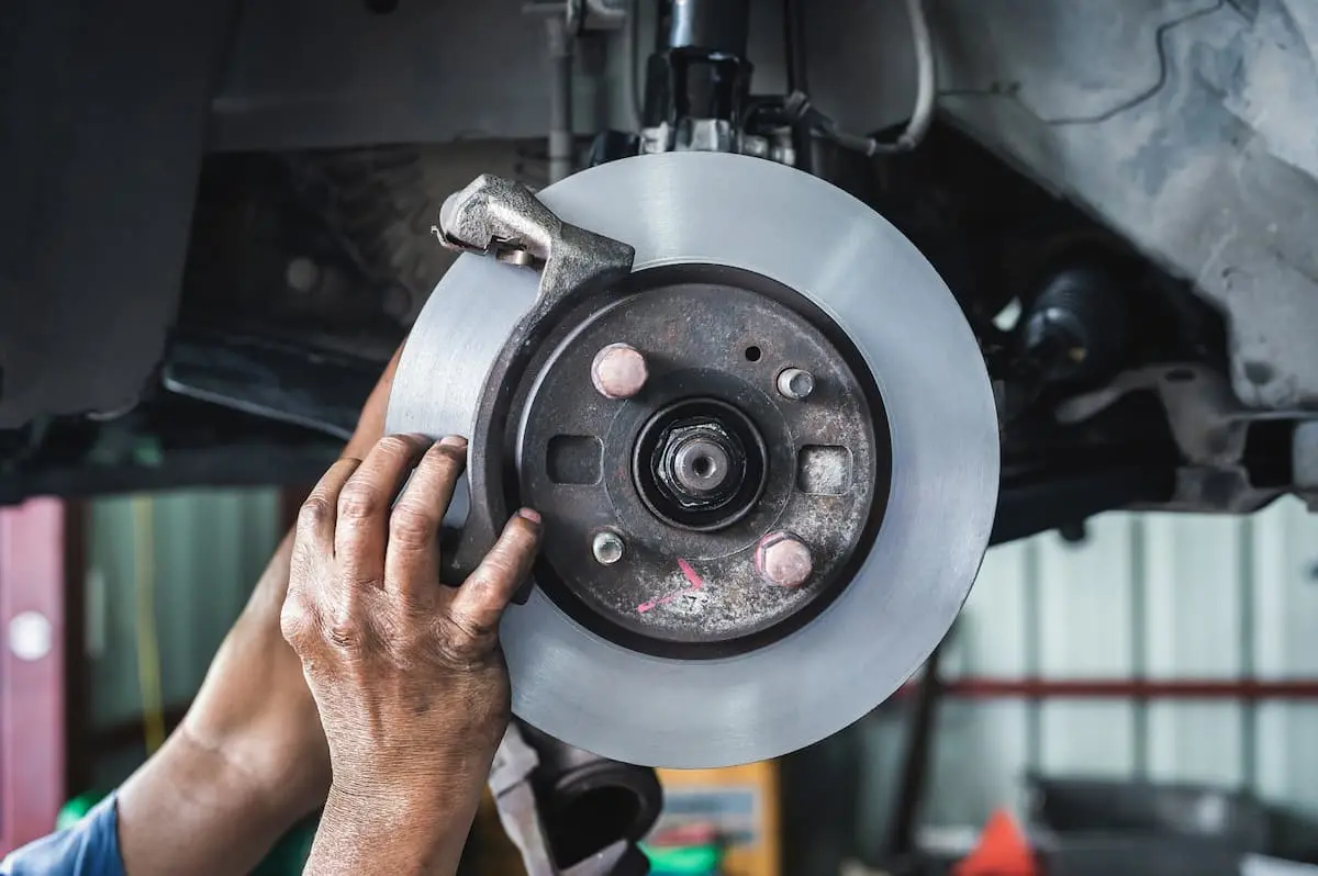 Professional brake rotor and caliper inspection by an auto mechanic to ensure vehicle safety and performance.